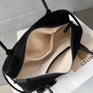 Detailed interior view of black suede Boston handbag with beige lining, metal zippers, and pockets.