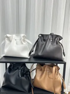 Primer plano de elegantes bolsos tipo saco de cuero suave con cordón en varios colores.
