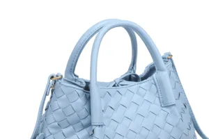 Detailed close-up of light blue woven leather handbag, premium intrecciato texture and hardware.