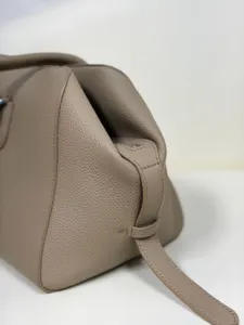 Detailed close-up of premium taupe pebbled leather bag, showing fine stitching and texture.