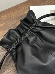 Close-up of black leather drawstring pouch bag, showing soft texture and fine stitching detail.