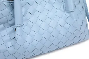 Light blue woven leather handbag detail, intrecciato texture close-up, luxury tote bag