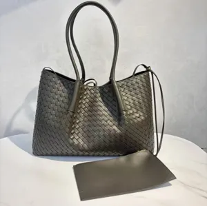 Woven leather tote bag with double top handles, shoulder strap, and matching small pouch.