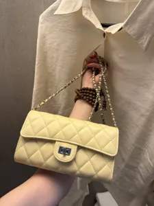 Quilted yellow leather chain shoulder bag with classic turn-lock closure and elegant strap.