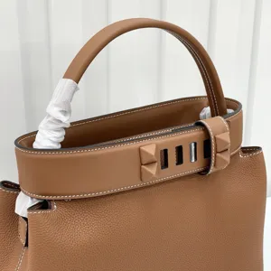 Brown leather top handle bag with pyramid studs and classic structured design for women.