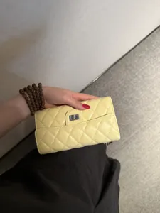 Detail shot of the yellow quilted leather wallet featuring a classic turn-lock closure.