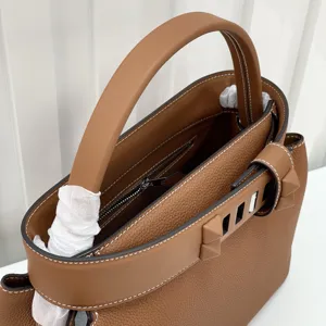 Brown leather top handle bag with metal pyramid studs and elegant contrast stitching.