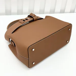 Classic brown leather top-handle bag with Togo texture, metal feet and chic pyramid stud strap.