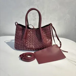 Burgundy woven leather tote bag with top handles, shoulder strap and matching small pouch.