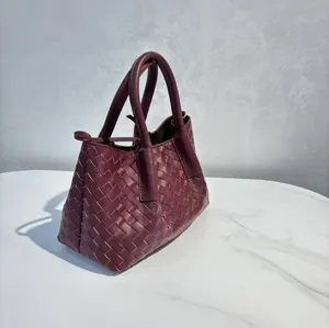 Luxury genuine leather woven handbag, elegant burgundy shoulder tote bag detail view.
