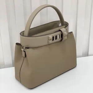 Elegant taupe leather top handle handbag with pyramid stud buckle design for women.
