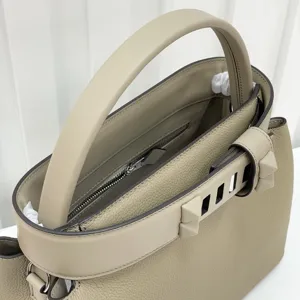 Close-up detail of luxury taupe leather top handle handbag with stylish side pyramid studs.