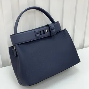 Close-up detail view of the dark blue genuine leather handbag with metallic pyramid stud strap.