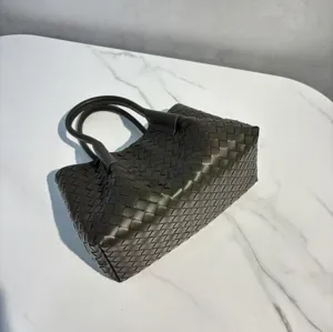 Detailed view of dark green woven leather tote bag, luxury style shoulder handbag close-up.