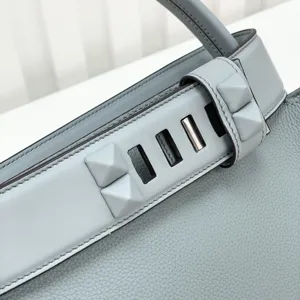 Grey leather handbag detail featuring stylish pyramid studs and premium craftsmanship.