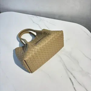 Detailed close-up view of beige leather woven tote bag, luxury intrecciato pattern design.