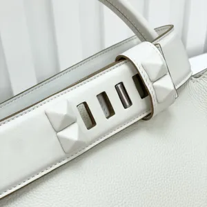 Luxury top layer cowhide leather handbag detail featuring iconic pyramid stud hardware strap.