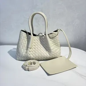 Detailed view of the woven leather tote bag with top handles, strap, and pouch accessory.