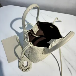 Detail view of the white leather woven tote bag showcasing craftsmanship and accessory set.