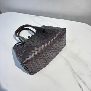 Dark brown woven leather tote bag detail, featuring classic intrecciato design and sturdy handles.