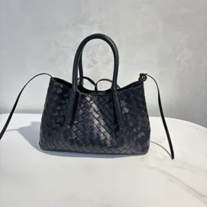 Black woven leather handbag detail shot showing the intricate craftsmanship and dual handles.