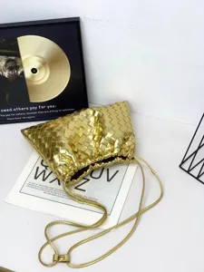 Close-up detail of luxury gold woven leather crossbody pouch bag with soft cloud shape.