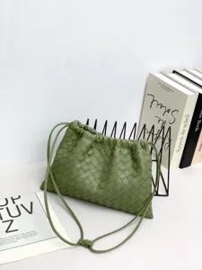 Detailed view of green woven leather shoulder bag with drawstring closure and fine straps.
