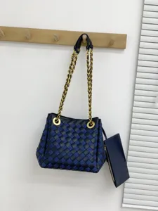 Vue détaillée du sac bandoulière en cuir tressé bleu foncé avec chaîne dorée et petite poche.