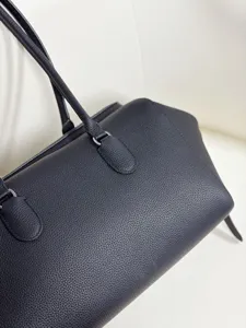 Detailed view of genuine leather black bowling shoulder bag, minimalist design texture.