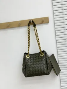 Vue détaillée du sac seau en cuir tressé vert foncé avec bandoulière chaîne et pochette.