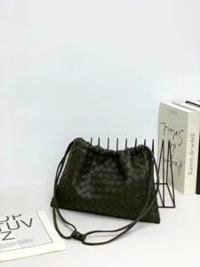 Dark green woven leather shoulder bag with drawstring closure and stylish casual design.
