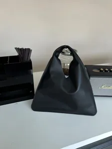 Détail de sac à main triangulaire en cuir noir, design géométrique minimaliste, accessoire élégant.