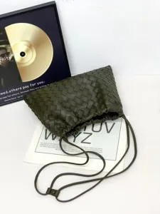 Close up detail of dark green woven leather pouch bag, stylish intrecciato crossbody.