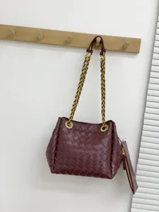 Sac seau en cuir tressé bordeaux avec bandoulière chaîne dorée épaisse et pochette.