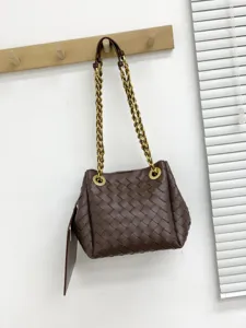 Sac seau bandoulière en cuir tressé fait main avec élégante bandoulière en chaîne métallique.