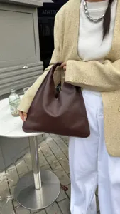 Sac hobo en cuir marron foncé vue de détail, forme triangulaire minimaliste, texture lisse.