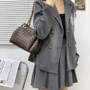 Élégant sac à épaule en cuir tressé marron avec bandoulière chaîne pour un style unique.