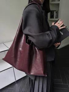 Minimalist soft leather tote bag detail, featuring rich dark red oil-wax finish and slouchy style.