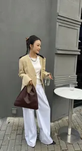 Sac à épaule triangulaire vintage en cuir pour femme associé à une tenue de blazer chic.