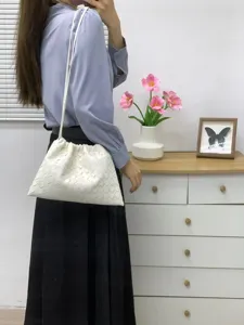 Detailed view of the elegant white woven leather shoulder crossbody bag showcasing a soft cloud shape.