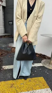 Gros plan détail du sac à main triangulaire en cuir noir élégant avec une texture fine.