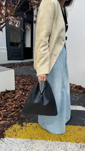 Vue détaillée du sac à main triangulaire en cuir noir associé à un look urbain chic.