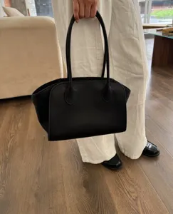 Close-up view of the minimalist black leather tote handbag, highlighting premium texture and craftsmanship.