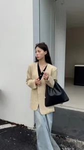 Élégant ensemble de blazer en tweed pour femme avec un sac à bandoulière en cuir chic.