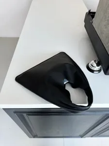 Vue détaillée du sac à main triangle en cuir noir montrant un design géométrique unique.