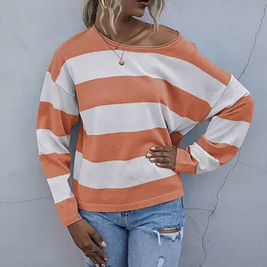 Detail view of loose knit striped sweater showing orange and white fabric texture