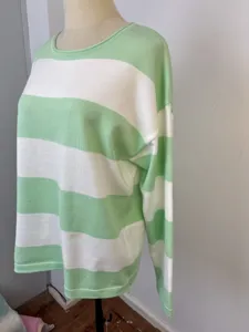 Detailed side view of a cozy green and white striped oversized crewneck knit sweater