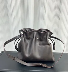 Detalle del bolso saco suave de cuero marrón oscuro, bolso bandolera con cordón ajustable y bolsillo.