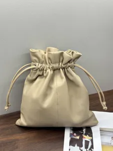 Detail view of soft beige genuine leather drawstring pouch, showing fine texture and metal eyelets.