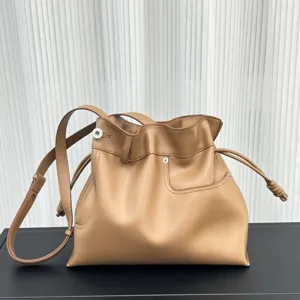 Bolso saco de cuero suave en color camello con cordón ajustable y correa para el hombro.